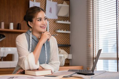 Asyalı terzi kadınlar ellerinde kalem tutuyorlar ve çizim için yeni moda koleksiyonu tasarlamayı düşünüyorlar..