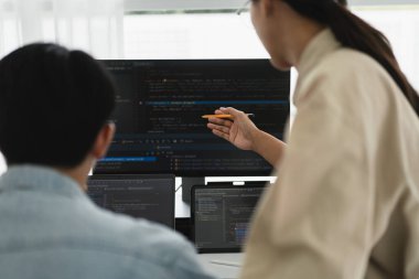 İki geliştirici web geliştirme programlama hakkında monitörde kodu kontrol etmeyi tartışıyor.