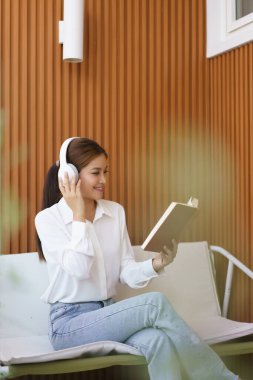 Kadın girişimci müzik dinliyor ve evde çalıştıktan sonra rahatlamak için kitap okuyor..