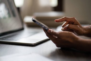 Akıllı telefondaki verileri araştıran ve yeni başlatılan proje hakkında dizüstü bilgisayar üzerinde çalışan kadın girişimci.
