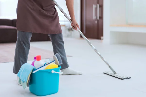 Maid using mop with bucket plastic of cleaner equipment to mopping cleanup floor in living room.