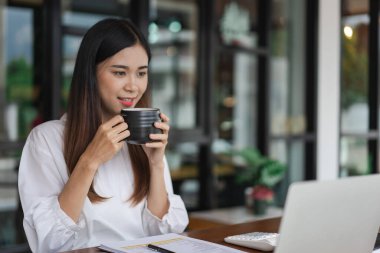 İş kadınları, ofis dışındaki yeni girişimleri analiz etmek için kahve içer ve dizüstü bilgisayarda veri okurlar.