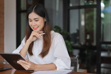 Tablet üzerinde veri okuyan ve ofis dışında çalışırken yeni bir başlangıç düşünen iş kadınları.
