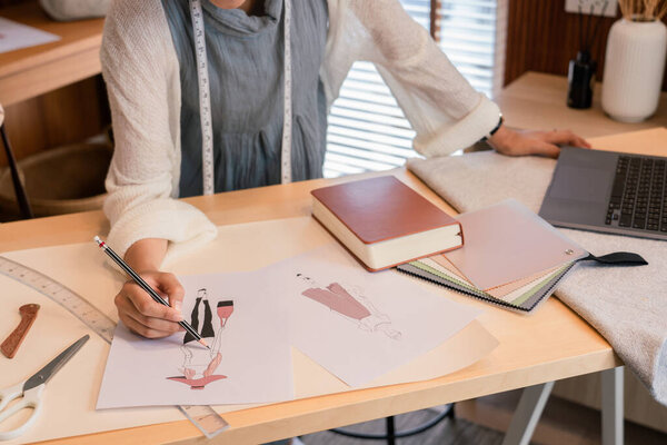 Asian tailor women working to design new fashion collection and sketching model dress in paper.