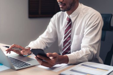 Akıllı telefon ve proje finansmanı analizi raporlarını kontrol ederken iş adamı dizüstü bilgisayarında veri tipi.