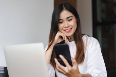 İş kadınları, ofis dışında çalışırken yeni bir başlangıç hakkında düşünmek için akıllı telefondan veri okurlar.