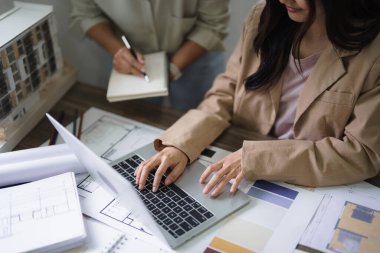 Kadın mimar tipi veriler ve not alırken iç yapı tasarım planını meslektaşlarına açıkla.