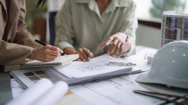 İki kadın mimar, iç mimarlık projesini planlar ve notlar üzerine tartışıyor..