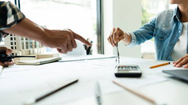 Proje üzerine inşaat projesi çizmek için geometri pusulası kullanan iki mühendis.