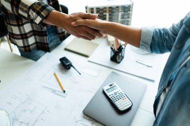 İnşaat projesiyle ilgili beyin fırtınasında başarılı olduktan sonra iki mühendis el sıkışıyor..