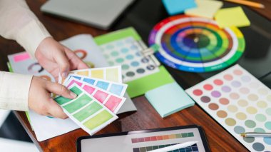 Proje tasarımı için tablet üzerindeki renkleri karşılaştırmak üzere renk örneklerini tutan yaratıcı grafik tasarımcısı.