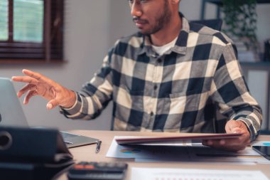 İşadamı ofis bilgisayarındaki mali ve muhasebe raporlarını kontrol etmek için iş belgesini okudu.