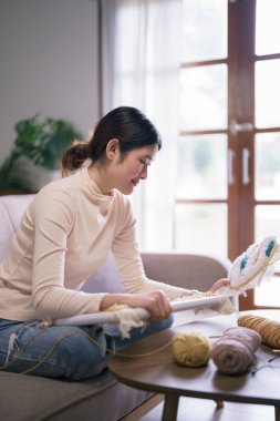 Genç Asyalı kadın, hobi olarak iğneli yumruk tekniğiyle nakışlı kumaş çerçeve taşıyor..