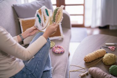 Genç Asyalı kadın, hobi olarak işlemeli kumaş çerçeve ve yumruk iğnesi tekniğine bakıyor..