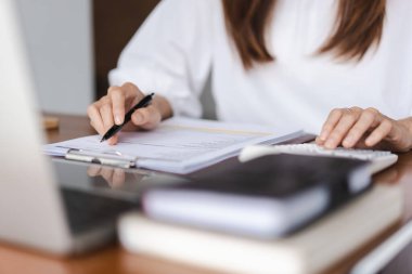 İş kadınları ofis dışında çalışırken mali belgeyi kontrol etmek için hesap makinesi kullanıyorlar.