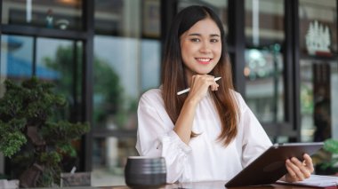 Tablet üzerinde veri okuyan ve ofis dışında çalışırken yeni bir başlangıç düşünen iş kadınları.