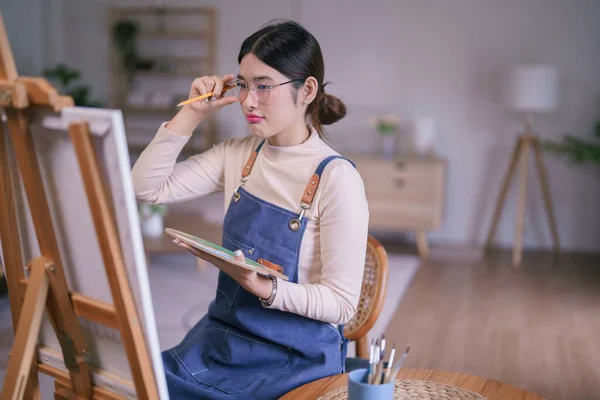 Młoda Azjatycka Artystka Dotykając Okularów Patrząc Płótnie Myślenia Pomysł Malarstwo — Zdjęcie stockowe