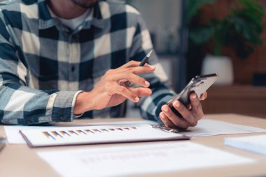 İşadamı iş dünyasının finans ve muhasebe raporlarını kontrol ederken akıllı telefondan bilgi okudu.