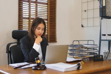 Law and justice concept, Young female lawyer reading contract on laptop and working in law office.