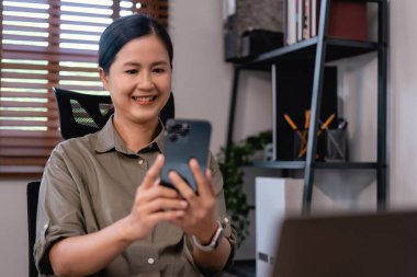 Sıradan iş kadınları ofiste dinlenirken sohbet etmek ve kahve içmek için akıllı telefon kullanıyor..