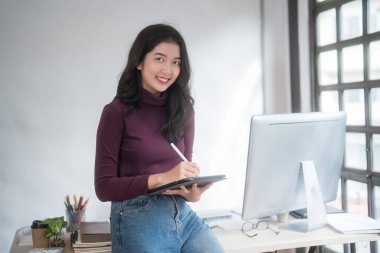 Grafik tasarımcısı serbest kadınlar yaratıcı fikirleri düşünerek ve logo markası çizmek için dijital tablet kullanarak ev stüdyosunda teknolojik ekipmanlarla grafik tasarımı hakkında çalışırken.