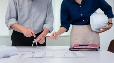 Planda pusulayı kullanarak inşaat projesini ortakla tartışan kıdemli mimar..