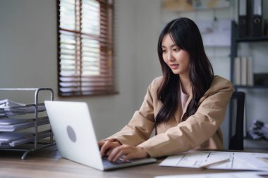Dizüstü bilgisayarında mimari plan yazmaya çalışan kadın mimar inşaat projesinin planıyla birlikte..