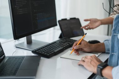 Web sitesini geliştirmek için programlama hakkında tartışırken iki geliştirici notlar yazıyor.