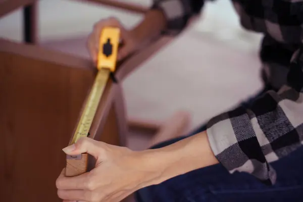 Women measuring length of chair with measure tape while assembling and renovation chair furniture.