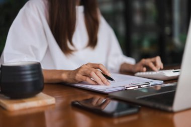 İş kadınları ofis dışında çalışırken mali belgeyi kontrol etmek için hesap makinesi kullanıyorlar.