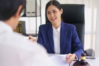 Avukat kadın, iş adamıyla sözleşmeyi ve yasal anlaşmayı açıklayan belgeyi kontrol ediyor..