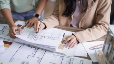 İki kadın mimar iç mimari hakkında tartışıyorlar. İnşaat projesi tasarlıyorlar ve plan üzerinde çizim yapıyorlar..