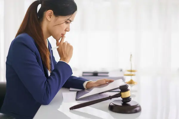 Lawyer woman thinking and reading business contract about legal agreement on tablet in legal office.