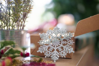 Noel ağacının yakınındaki ahşap masanın üzerinde top topu ve kostüm kutulu kar taneleri Noel bayramı ve kış mevsimlerini kutlamak için hazırlanıyor..