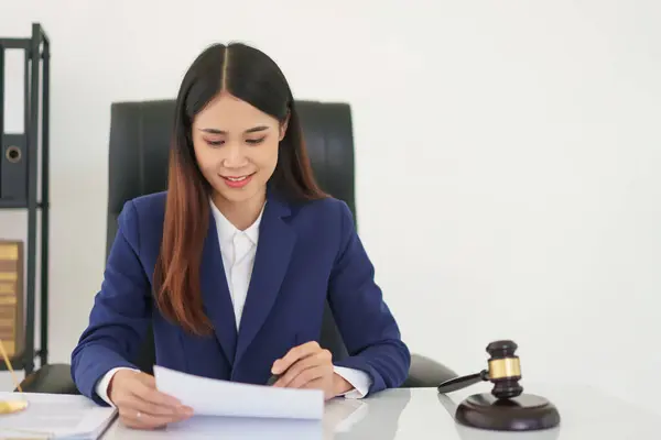 Lawyer woman read business contract with law agreement and writing data on document in legal office.