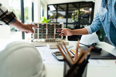 Ofisteki inşaat projesinin kondominyum modeli hakkında iki mühendis tartışması ve beyin fırtınası.