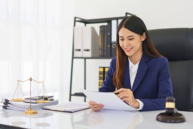 Avukat kadın, hukuk anlaşmasıyla iş sözleşmesi okudu ve hukuk bürosundaki belgelere veri yazdı.