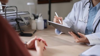 Endişeli Asyalı hasta kadınlar doktorlara psikolojik sağlık sorunlarını açıklarken, kadın psikologlar da ilaç ve ruh sağlığı terapisi hakkında notlar yazıyorlar..