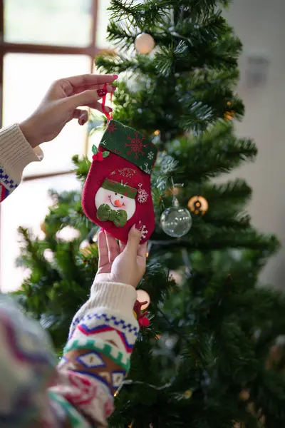 サンタクロースの靴下やクリスマスツリーのおもちゃを飾るセーターの若いアジアの女性は クリスマスツリーを準備しながら 家でクリスマスのお祝いの休日や冬の季節を祝います — ストック写真