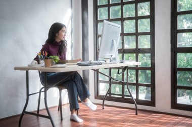 Grafik tasarımcı serbest kadınlar dijital tablet üzerinde logo markası çizmek için yaratıcı fikirler düşünüyor ve ev stüdyosundaki teknolojik ekipmanlarla grafik tasarımı hakkında çalışırken bilgisayarda yazı yazıyorlar..