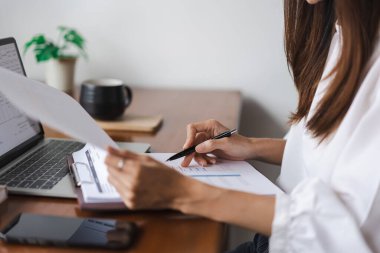 İş kadınları ofis dışında çalışırken dizüstü bilgisayarda veri okuyorlar ve finans belgelerini kontrol ediyorlar.