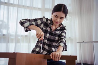 Kadınlar mobilya yapımında sandalye montajı ve onarımı için vida takmak için tornavida kullanırlar.