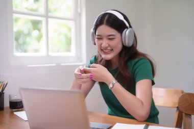 Genç Asyalı kadın öğrenciler internetteki bilgisayar dersinde video sohbet yoluyla kulaklık takıyor ve evden bilgi uzaktan eğitimini öğrenme üzerine ders çalışırken ve ders çalışırken iletişim kuruyorlar..