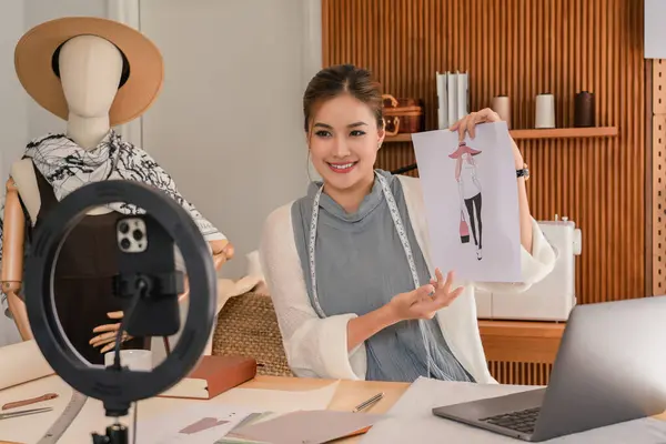 Asian tailor women explain about sketching of new dress collection and recording video for blogger.