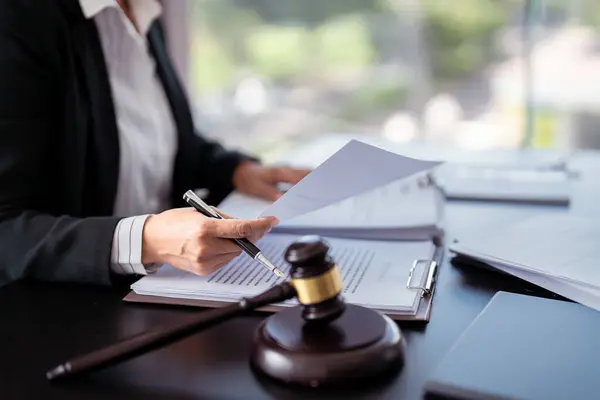 Lawyer businesswoman holding document to reading lawsuit and checking about financial business data while analysis about legislation agreement and terms data of business contract in law firm.