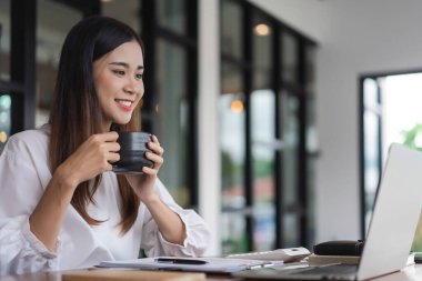 İş kadınları, ofis dışındaki yeni girişimleri analiz etmek için kahve içer ve dizüstü bilgisayarda veri okurlar.
