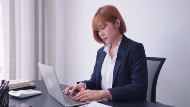 彼女のコンピュータのノートパソコンに取り組んでいる自信のあるアジアの実業家は 彼女の仕事に熱心に焦点を当てるために分析的思考を使用しています 彼女は強力な仕事倫理と決意高品質の4K映像を示しています — ストック動画
