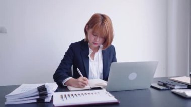 Kendine güvenen Asyalı bir iş kadını, özverili çalışma alanında hayati önem taşıyan şirket bilgilerini dizüstü bilgisayarına, sarsılmaz bir dikkatle kaydeder..