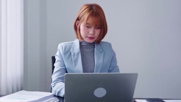 一位精力充沛的亚洲女商人 满腔热情地通过电话交谈 同时还在笔记本电脑上工作 举止活泼而活泼 高质量的4K镜头 — 图库视频影像