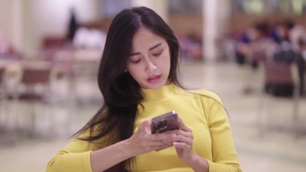 Miła Azjatycka Studentka Siedząca Przy Stole Korzystająca Telefonu Komórkowego Lub — Wideo stockowe